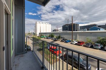 A balcony with a view of a parking lot and industrial buildings. at RiDE at RiNo Apartments, Denver, CO, 80216